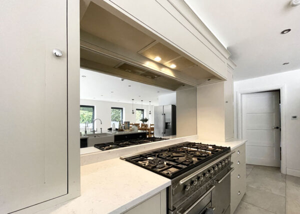 A white kitchen with a stove featuring Toughened Mirrors as splashbacks.
