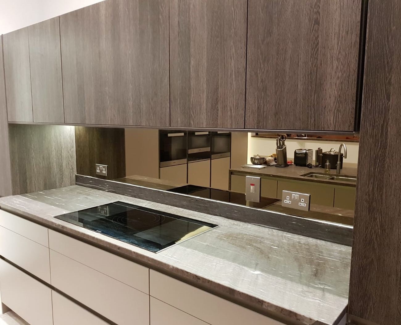 A kitchen with wooden cabinets and a stainless steel stove featuring glass splashbacks for added elegance.
