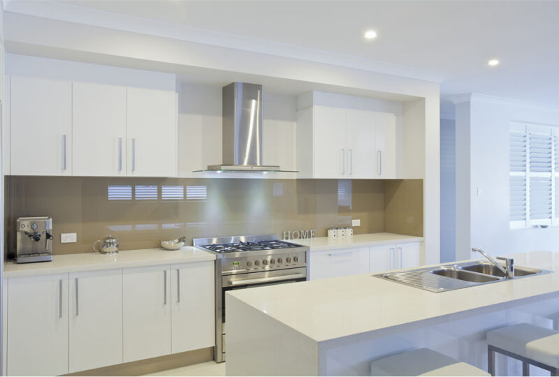 Modern kitchen with white cabinetry, stainless steel appliances, and a central island with stools. neutral tones and natural light create a bright and clean space.