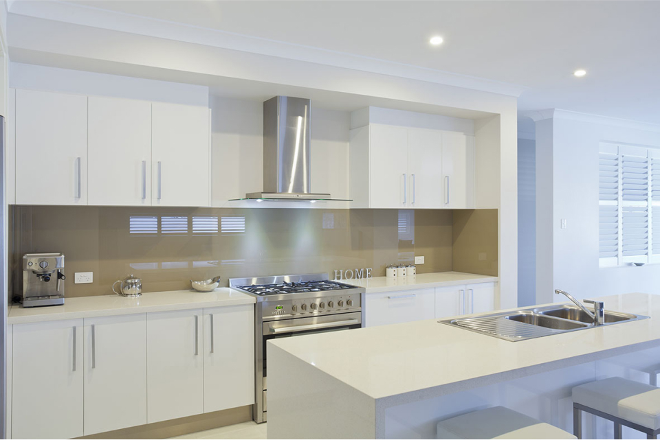 Modern kitchen with white cabinetry, stainless steel appliances, and a central island with stools. neutral tones and natural light create a bright and clean space.