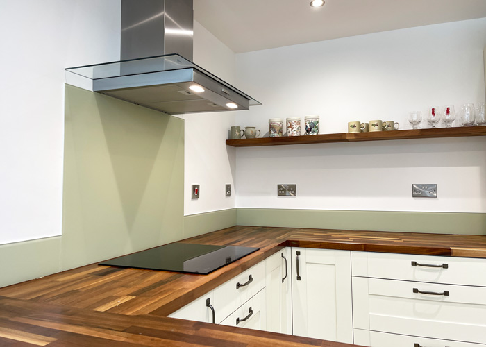Modern kitchen interior with new white cabinets, wooden countertops, and stainless steel extractor hood.