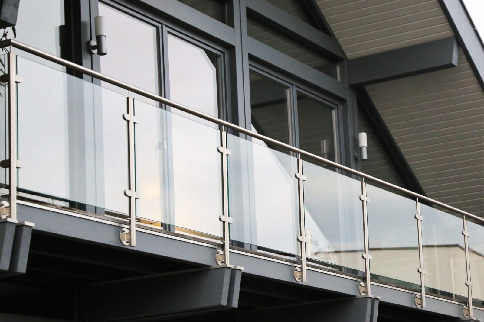 Modern building facade featuring large glass windows and a metal balcony railing, with new architectural details in grey tones.
