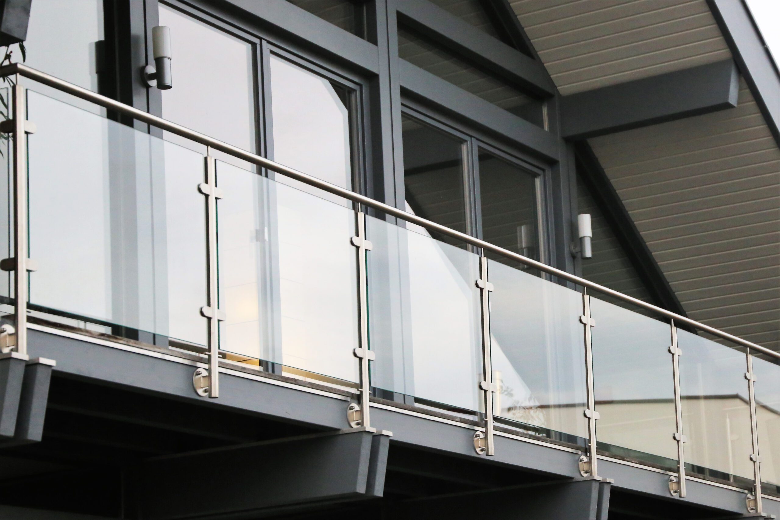Modern building facade featuring large glass windows and a metal balcony railing, with new architectural details in grey tones.